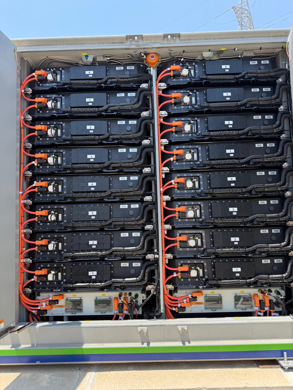 Battery modules and orange electrical connections inside an open storage container